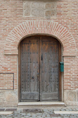 Fototapeta na wymiar brick facade with round arch and old wooden door