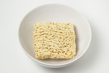 Dry instant noodles in a plate on a white background. Fast food. Modern food.