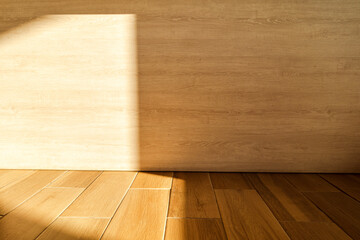 The sun shines on the corners of the wood wall and floor