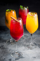 different lemonades in glasses on grey table side view, verical