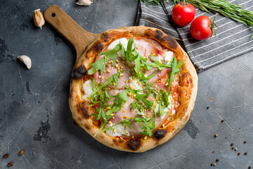 Pizza with Parma ham and arugula top view on grey table