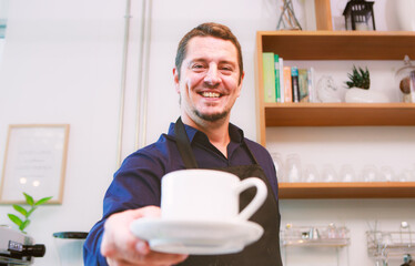 Portrait of a Caucasian man holding a cup of coffee served to a customer