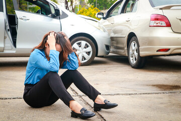 stressed asian woman She sat on the concrete road. A car crashes on the road during rush hour. The...