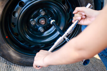 Woman changing car wheels herself An accident happened because the wheel was hit by a nail causing the tire to flatten. Concept of car accident insurance.