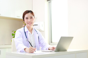 Asian female doctor sitting in office Write a record of the patient's treatment. Online treatment concept. Hospital medical services