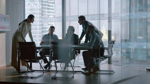 Chief corporate manager talking with team at desk in meeting room