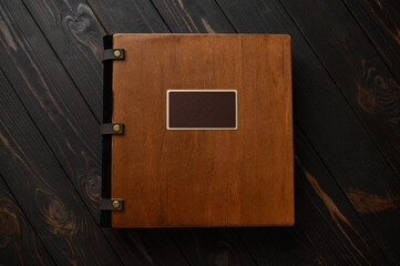 An old photo album with a wooden cover and a shield on a rustic table. free logo - obrazy, fototapety, plakaty