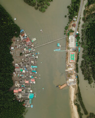 Top down aerial view of a fishing village with a football field in the mangrove jungle
