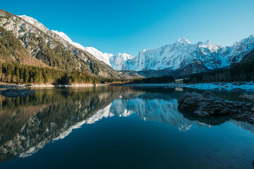 Fototapeta na wymiar Beautiful reflection of the mountains in the lake. Lago di Fusine in winter time on the border of Slovenia and Italy.