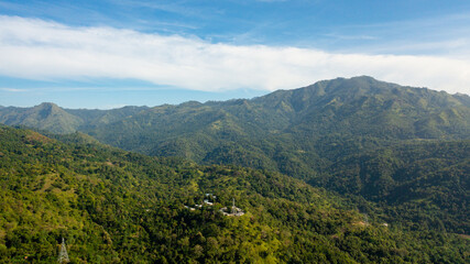 Fototapeta premium Aerial view of mountain peaks covered with clouds against the blue sky.