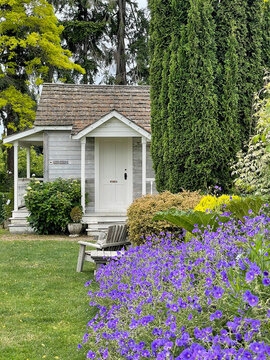 White cottage with purple flowers in the foreground 