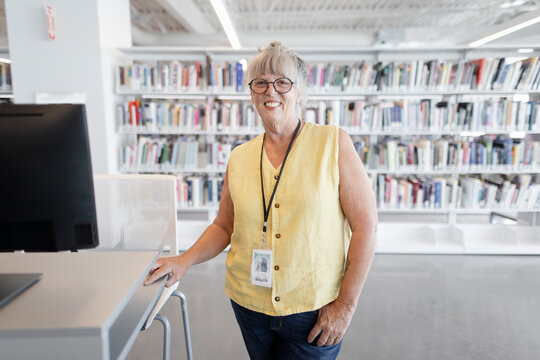 Portrait happy female librarian with lanyard in library