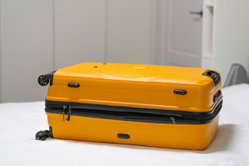 Yellow closed suitcase lies on the bed in white room no people copy space mockup