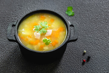 Instant pot bacon split pea soup in cast iron pot on dark background. Top view, copy space, flat lay.