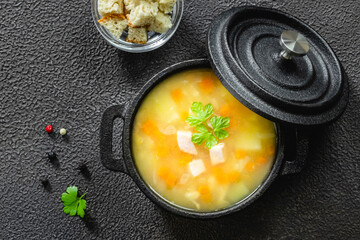 Split pea ham soup in cast iron pot on dark background. Top view, copy space, flat lay.