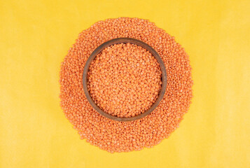 Fototapeta na wymiar Red lentils pile isolated. Dry orange lentil grains, heap of dal, raw daal, dhal, masoor, Lens culinaris or Lens esculenta on yellow background. Red lentil in wooden bowl. Musoorir Dal India.