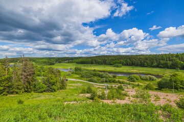 Amazing panoramic view of green summer landscape with forests, fields and river against blue sky and white clouds. Sweden.