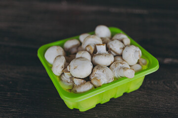 Mushrooms champignons in a green bowl on the table