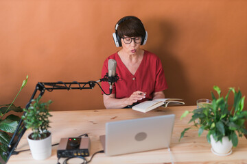 Middle-aged female radio presenter talking into the microphone and reading news - radio broadcast...