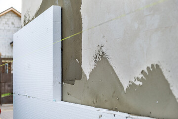 Installation of styrofoam insulation sheets on house facade wall for thermal protection