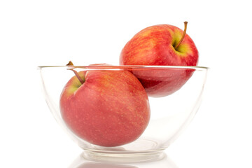 Two juicy red apples in a glass bowl, close-up, isolated on a white background.