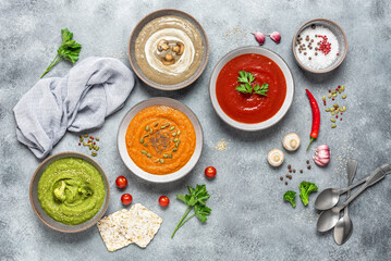 Colored vegetable soups. Set of vegetarian soups. The concept of organic food. Gray concrete background. View from above.