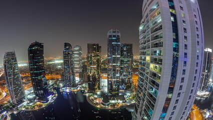 Obraz premium Panorama of tall residential buildings at JLT aerial night timelapse, part of the Dubai multi commodities centre mixed-use district.