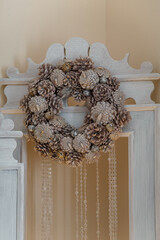 Merry Christmas wreath from shiny painted pine cones, closeup. Winter holidays celebration, decorative element for interior