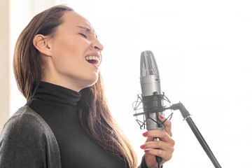 Young Japanese or European long-haired brunette woman emotionally sincerely singing lyric song to...