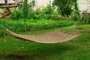 Hammock stands in the green garden of the cottage. The concept of vacation in the summer or in warm countries.
