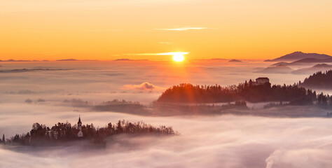 Church and villages hiding in the early morning fog. A misty sunrise in the countryside.