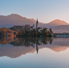 Fototapeta na wymiar Lake Bled at Sunrise. Church, castle and the mountains are basking in the morning sun