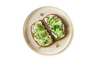 Breakfast, cereal bread sandwiches, cream cheese, sliced cucumber, with micro greenery on a light table, close-up, top view, selective focus, no people,