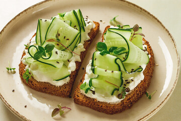 Breakfast, cereal bread sandwiches, cream cheese, sliced cucumber, with micro greenery on a light table, close-up, top view, selective focus, no people,