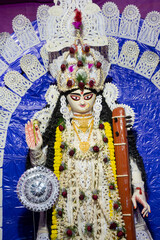 Fototapeta premium Idol of Goddess Saraswati with veena, a musical instrument, at Kolkata, West Bengal, India. Saraswati is Hindu goddess of knowledge, music, art, wisdom, and learning.