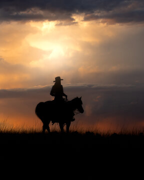 A cowgirl rides her horse at sunrise. 