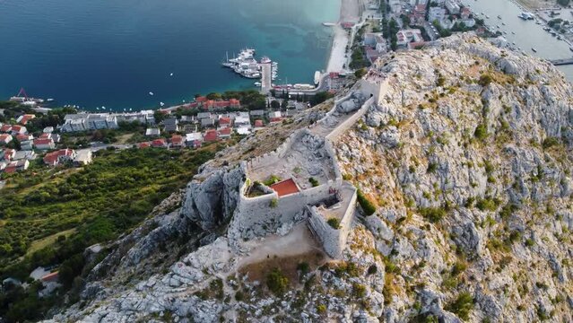 Omis, Croatia. Aerial view on old fort at mountain near old pirate city Omis. Castle on mountains over Adriatic coast at sunset. Top panoramic view high quality 4k.