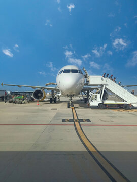 Palermo, Italy: Passengers or people deboarding Airbus A320 airplane at Palermo airport against blue sky during day time