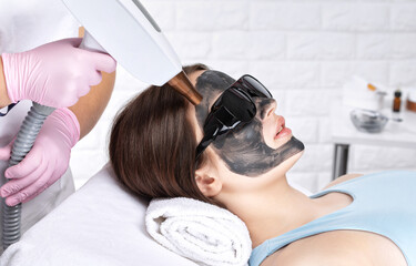 Carbon peeling procedure to beautiful blue-eyed girl in a beauty salon. Hardware cosmetology...