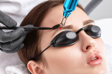 Removal of permanent makeup on the eyebrows of a woman.Carbon face peeling in a beauty salon....