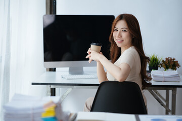 Businesswoman is holding and drinking a cup of coffee in office space