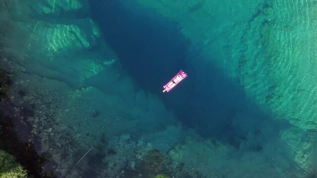 Aerial view of young woman swimming on the inflatable in source of the Cetina River (izvor Cetine) near Mount Dinara called the Blue Eye (Modro oko).
