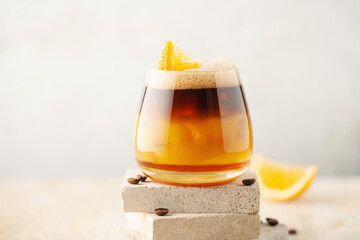Bumble coffee with ice on a stone background. Espresso, orange juice and syrup in layers in...