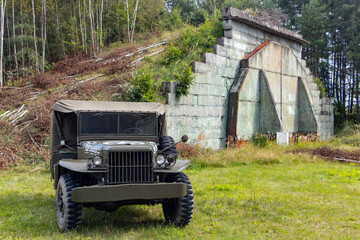A historic US-made army off-road car stands in front of Hangars at a former military airport.