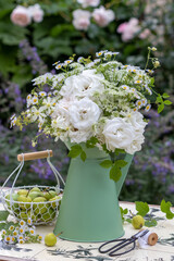 Blumenstrauß mit weißen Rosen, Wildastern und Wilden Möhren im vintage Krug im Garten