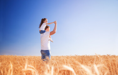 Naklejka na ściany i meble Happy father and daughter walk in the summer field. Nature beauty, blue sky and field with golden wheat. Outdoor lifestyle. Freedom concept.