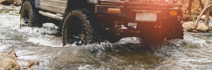 Part of an off-road vehicle driving through a fast flowing stream. Adventure concept. Living. © PIPAT