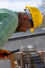 bricklayers with yellow helmet and protective glasses building an iron beam for reinforced concrete - PHOTO SESSION: WORK IN CONSTRUCTION