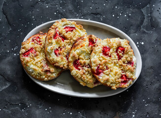Puff pastry buns with ricotta, strawberries and crumble on a dark background, top view