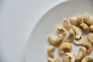 Cashew nuts on a white plate in a group of loose